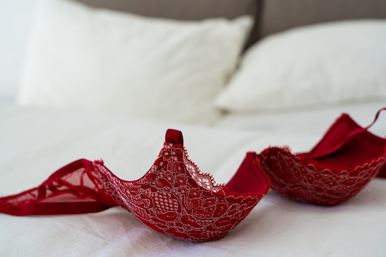 A red lace bra elegantly laid on a white bed in a stylish bedroom setting.